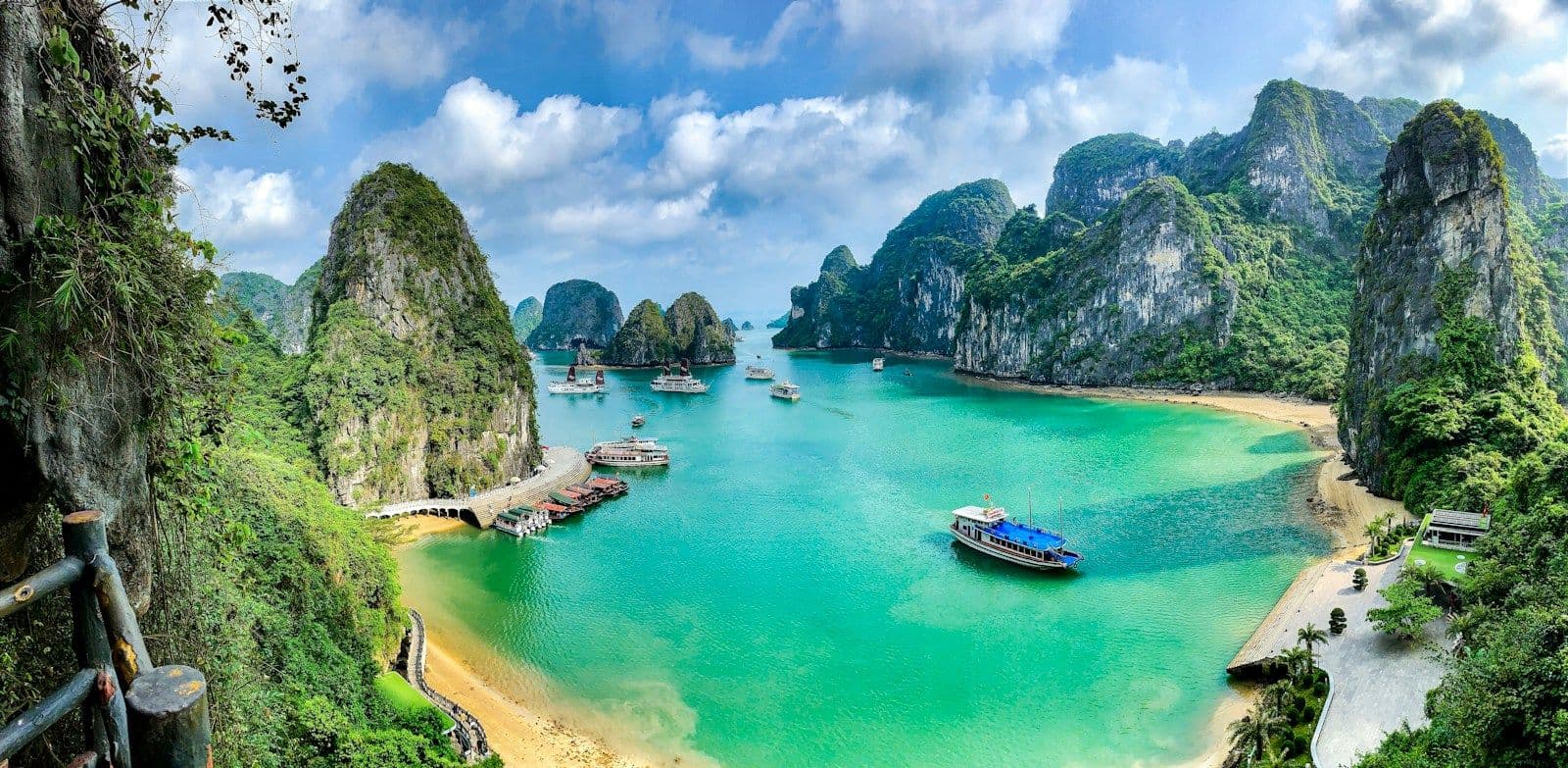 Boote in der türkisfarbenen Halong-Bucht zwischen bewachsenen Kalkfelsen